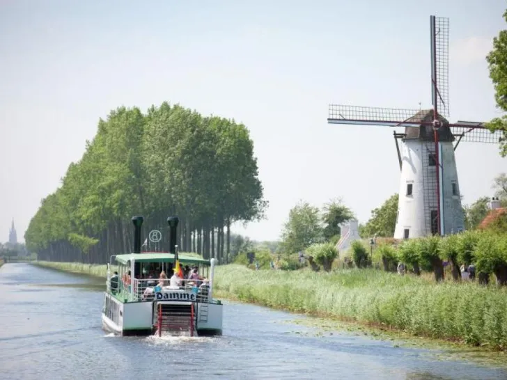 The Lamme Goedzak boat on the canal between Bruges and Damme with a windmill behind